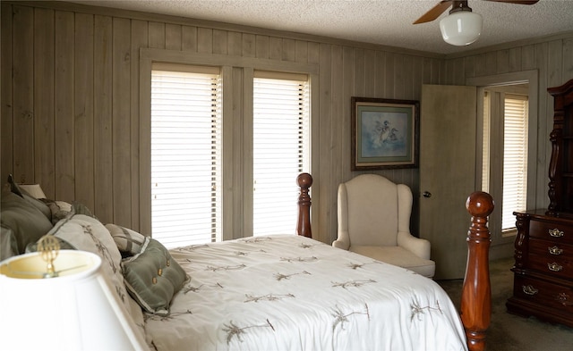 bedroom featuring crown molding, wooden walls, ceiling fan, and a textured ceiling