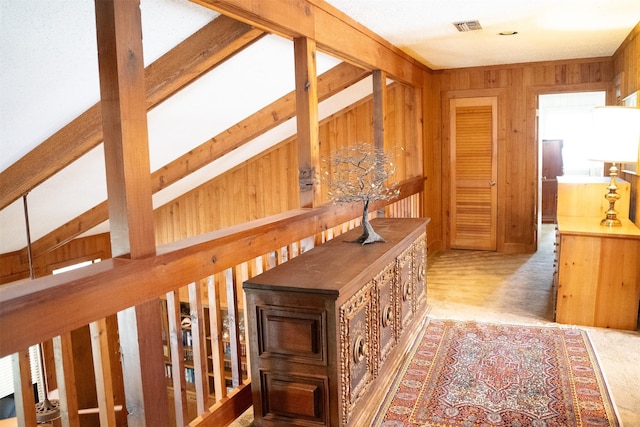 corridor with carpet, visible vents, and wood walls