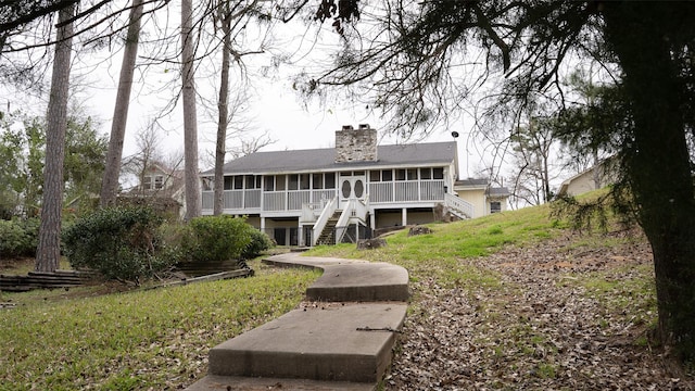 rear view of property featuring a sunroom, a chimney, and stairway