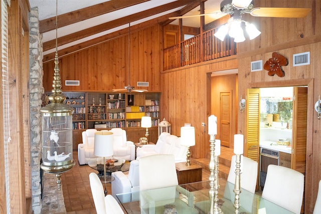 dining space with wooden walls, visible vents, and beam ceiling