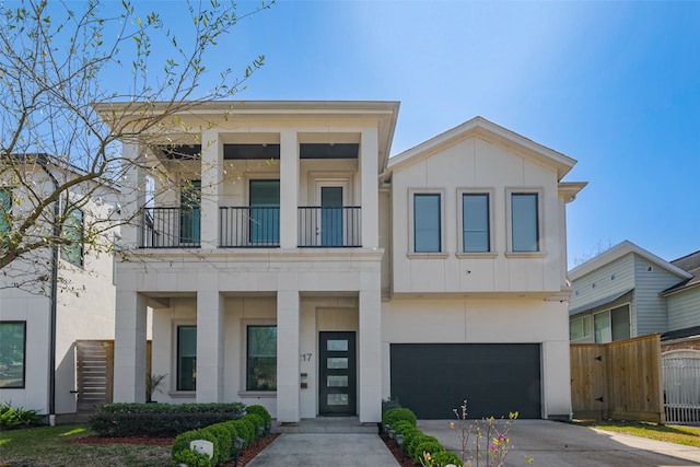 view of front of house featuring concrete driveway, board and batten siding, fence, a balcony, and a garage