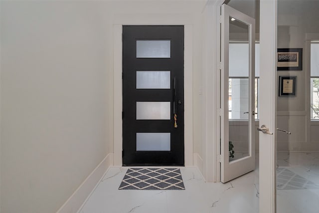 foyer with marble finish floor, a wealth of natural light, and baseboards