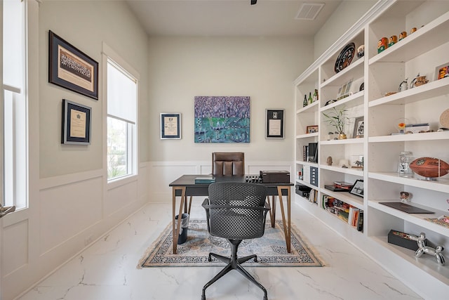 office with marble finish floor, visible vents, a decorative wall, and a wainscoted wall