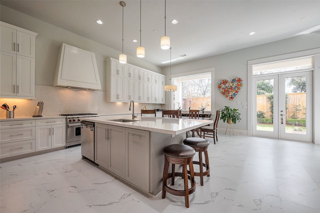 2217 W Main St, Houston, TX 77098 - kitchen featuring appliances with stainless steel finishes, light marble finish floors, extractor fan, recessed lighting, and a kitchen island with sink