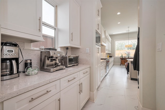 2217 W Main St, Houston, TX 77098 - kitchen with light marble finish floors, white cabinetry, light stone counters, recessed lighting, and hanging light fixtures
