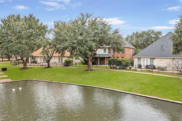 view of property's community featuring a water view, fence, and a lawn