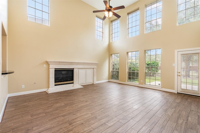 unfurnished living room featuring a high end fireplace, baseboards, and wood finished floors