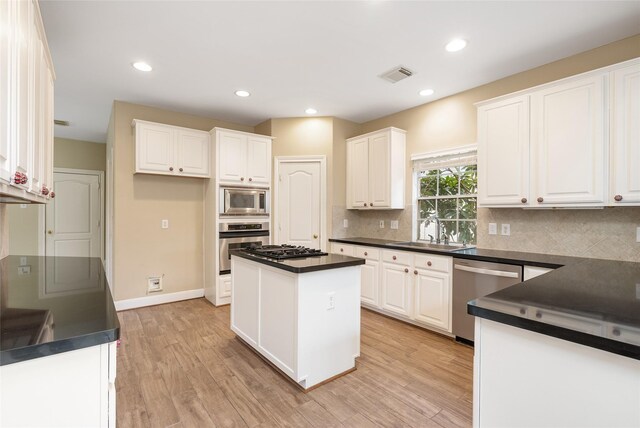 kitchen featuring visible vents, dark countertops, appliances with stainless steel finishes, light wood-style floors, and a sink