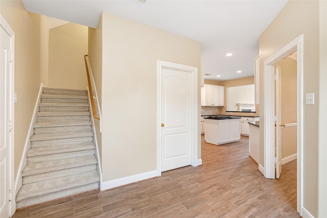 stairway featuring recessed lighting, wood finished floors, and baseboards