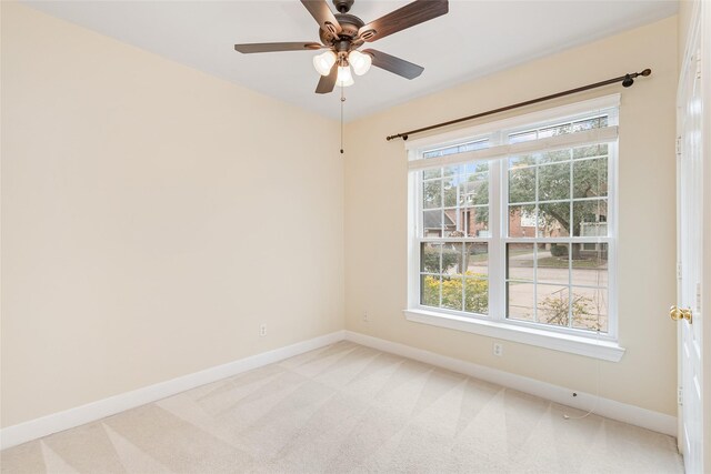 spare room with light carpet, ceiling fan, and baseboards