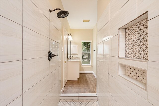 bathroom featuring visible vents, a tile shower, and vanity