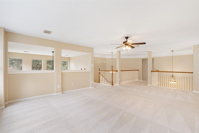 unfurnished room featuring light carpet, visible vents, baseboards, and ceiling fan with notable chandelier