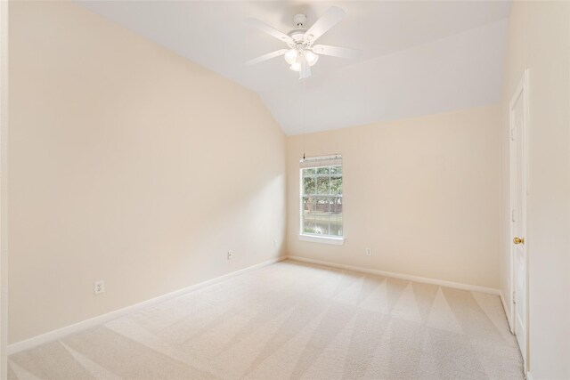 empty room featuring a ceiling fan, lofted ceiling, light colored carpet, and baseboards