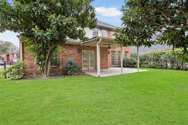 rear view of house featuring french doors, brick siding, a yard, a patio, and ceiling fan