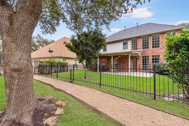 view of front of house featuring roof with shingles, brick siding, a front yard, a patio area, and fence