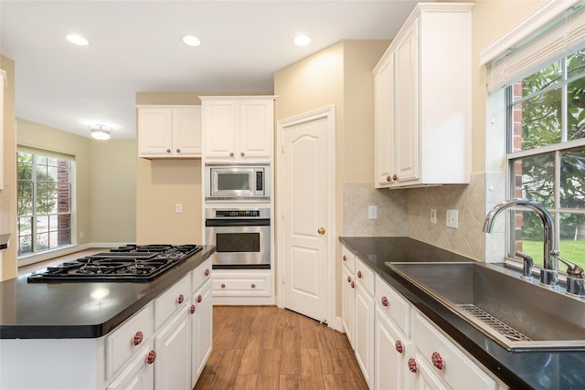 kitchen with dark countertops, white cabinets, stainless steel appliances, and a sink