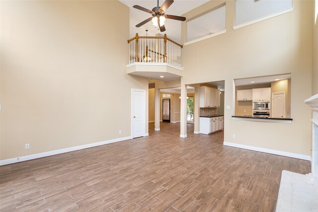 unfurnished living room with light wood finished floors, a fireplace, a ceiling fan, and baseboards