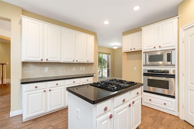 kitchen featuring stainless steel appliances, light wood-style floors, dark countertops, and decorative backsplash