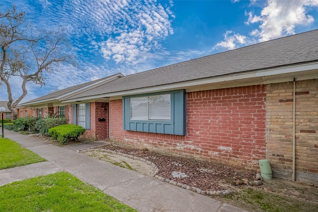 view of front of house with brick siding and roof with shingles