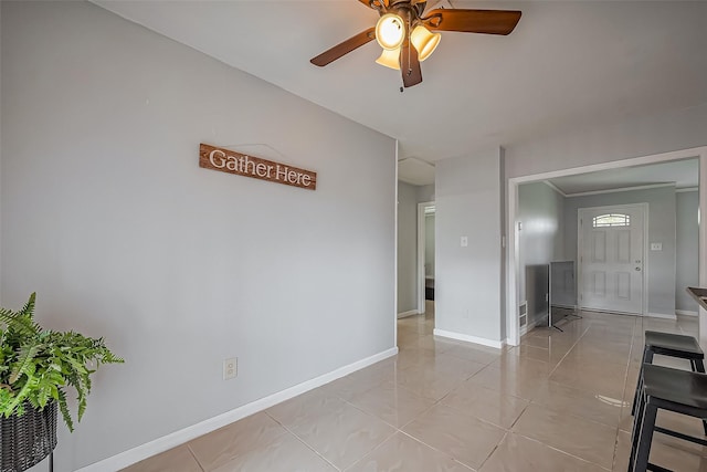 empty room with light tile patterned floors, a ceiling fan, and baseboards