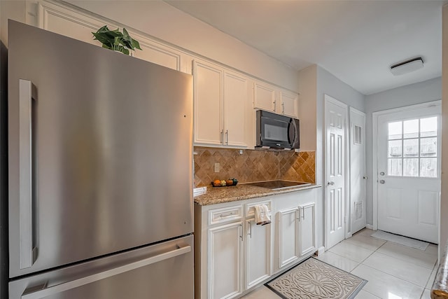 kitchen featuring white cabinets, decorative backsplash, light stone counters, black appliances, and light tile patterned flooring