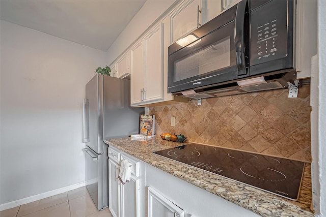 kitchen with light tile patterned floors, backsplash, white cabinetry, light stone countertops, and black appliances