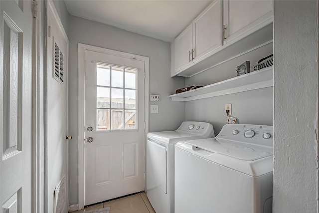 washroom featuring cabinet space, washing machine and dryer, and visible vents