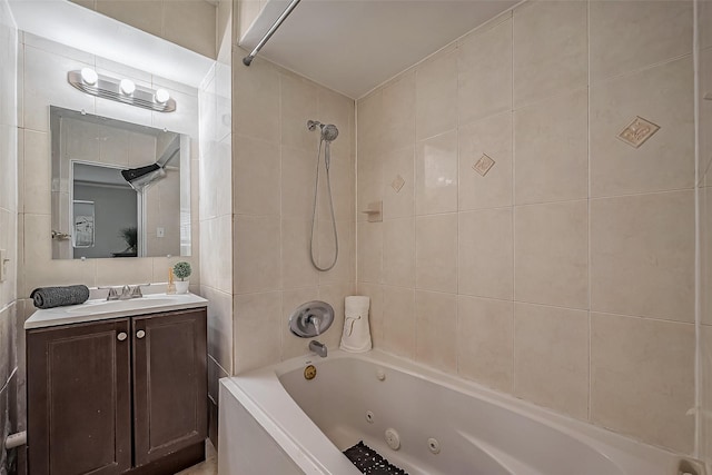 bathroom with a combined bath / shower with jetted tub, tile walls, and vanity