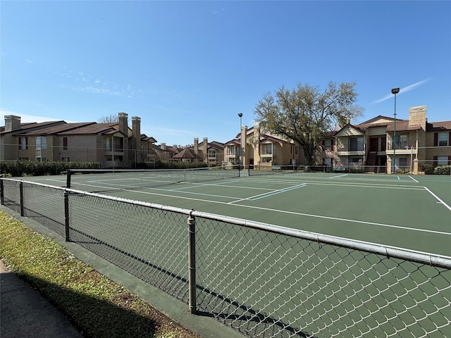 view of tennis court with a residential view and fence