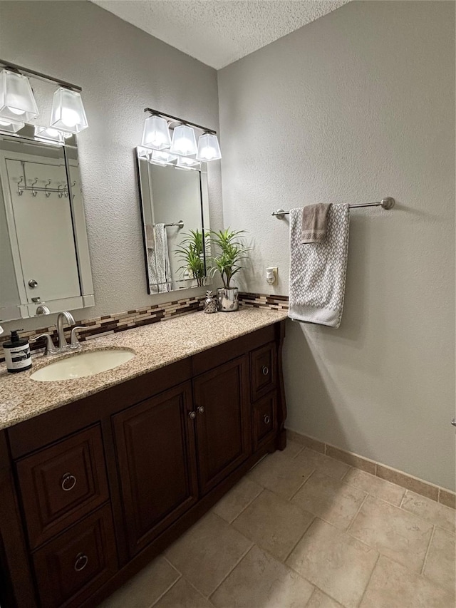 bathroom featuring baseboards, a textured ceiling, and vanity