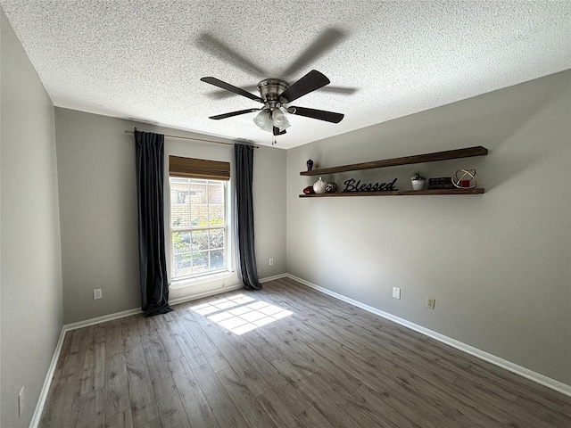 unfurnished room featuring a textured ceiling, ceiling fan, wood finished floors, and baseboards