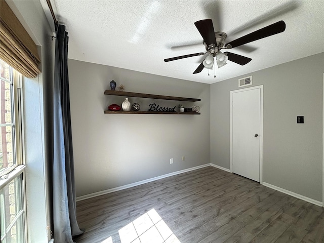 unfurnished room featuring a textured ceiling, visible vents, and wood finished floors