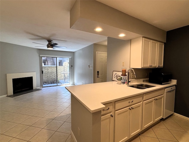 kitchen featuring dishwasher, light countertops, a fireplace, a sink, and light tile patterned flooring