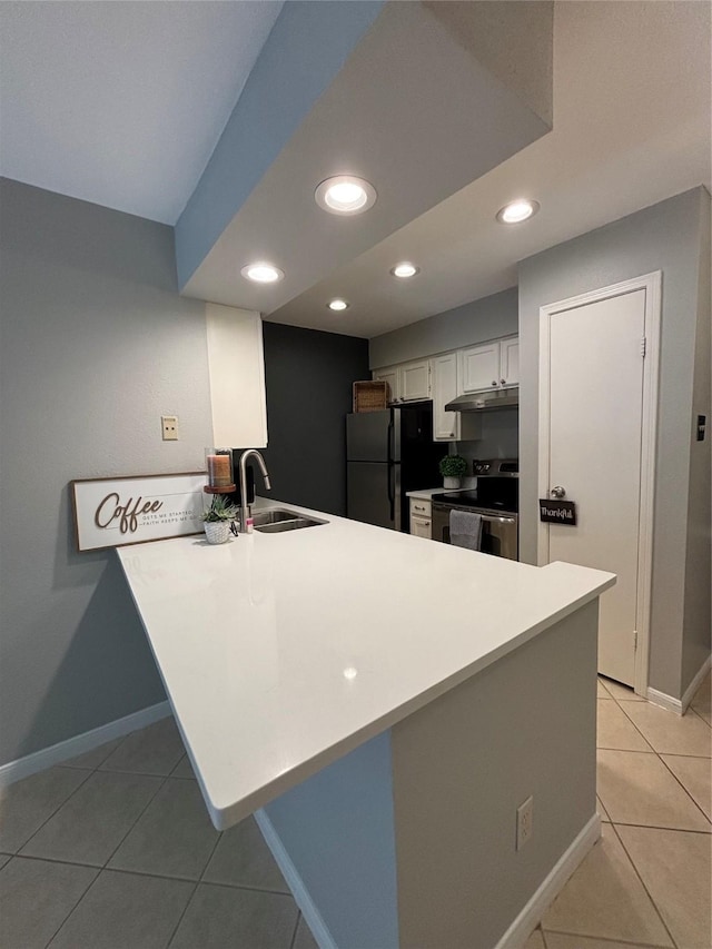 kitchen with freestanding refrigerator, white cabinetry, a sink, stainless steel range with electric stovetop, and a peninsula