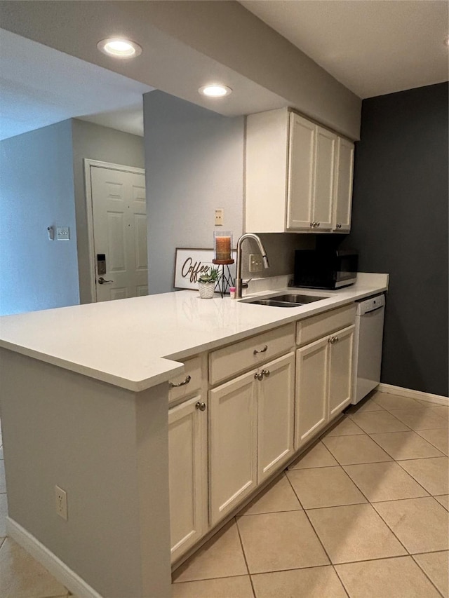 kitchen with light tile patterned floors, light countertops, white dishwasher, a sink, and a peninsula