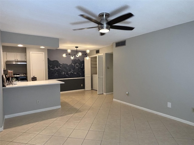 kitchen with light tile patterned floors, visible vents, stove, under cabinet range hood, and ceiling fan with notable chandelier