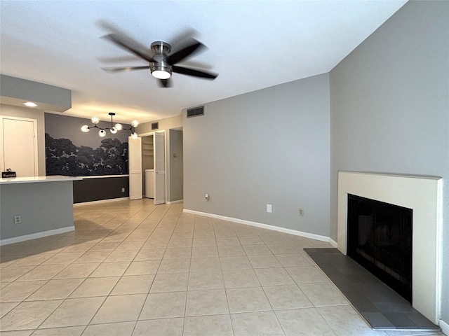 unfurnished living room with a fireplace, light tile patterned floors, visible vents, baseboards, and ceiling fan with notable chandelier