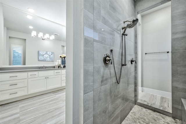 full bath featuring visible vents, a tile shower, and vanity