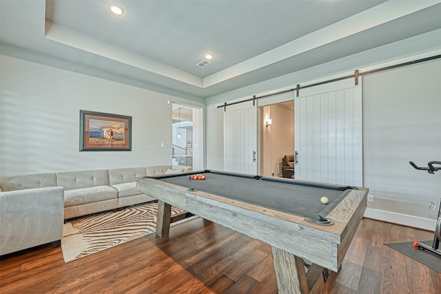 rec room with a barn door, visible vents, a raised ceiling, wood finished floors, and recessed lighting