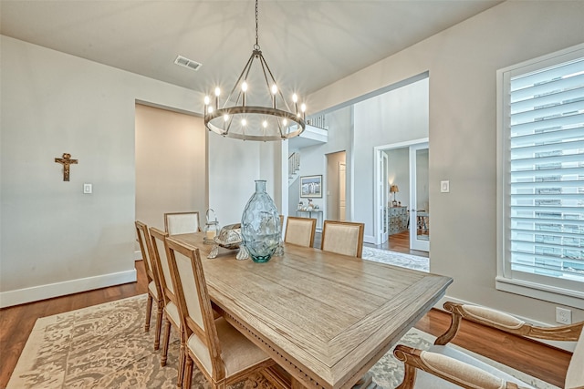 dining room featuring a notable chandelier, wood finished floors, visible vents, and baseboards