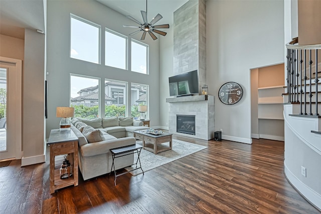 living room with a healthy amount of sunlight, baseboards, wood finished floors, and a tile fireplace