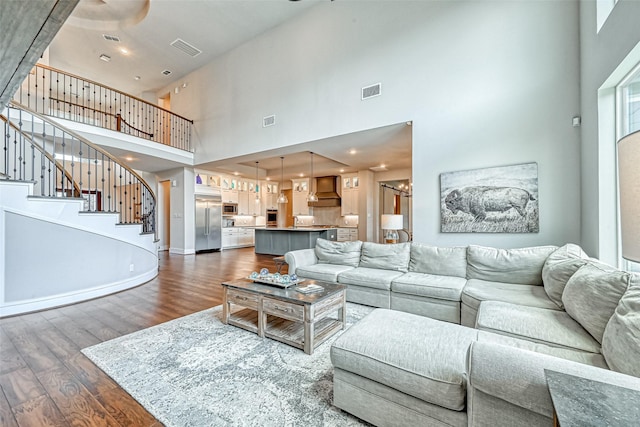 living room with a chandelier, dark wood-style flooring, visible vents, baseboards, and stairs