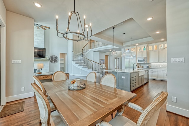 dining space with dark wood-type flooring, a raised ceiling, stairway, and baseboards