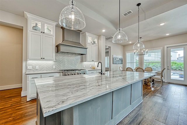 kitchen with dark wood-style flooring, custom exhaust hood, visible vents, a sink, and range