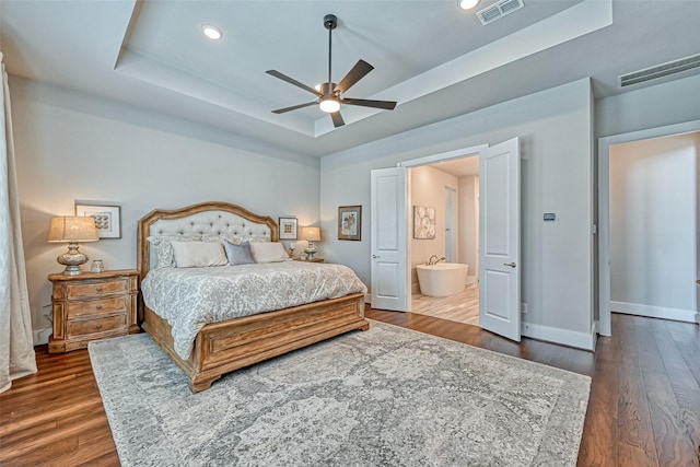 bedroom featuring visible vents, a tray ceiling, and dark wood-style flooring