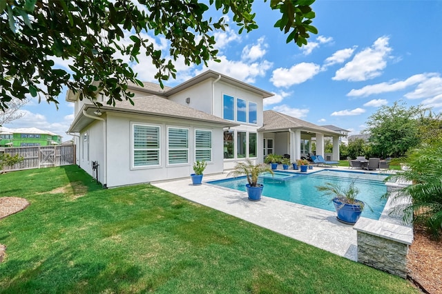 rear view of house featuring stucco siding, a lawn, a patio area, fence, and an outdoor pool