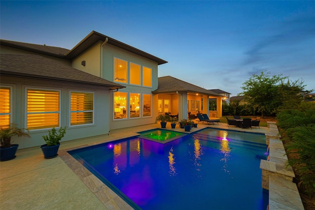 pool at dusk with a patio area and an outdoor pool