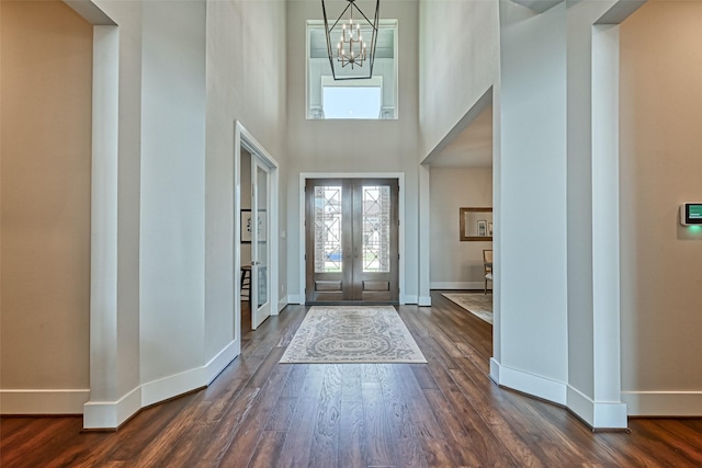 foyer entrance featuring an inviting chandelier, baseboards, dark wood-style flooring, and french doors