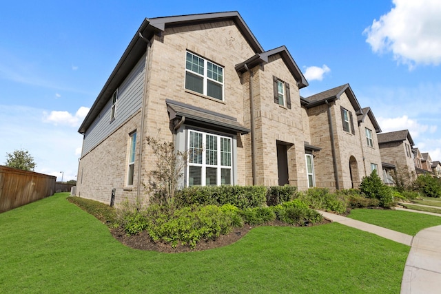 view of front of home with fence, a front lawn, and brick siding