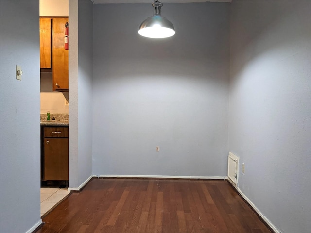 unfurnished dining area with wood finished floors, visible vents, and baseboards